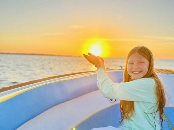 child-holding-sun-up-sunset-boat-clearwater-beach