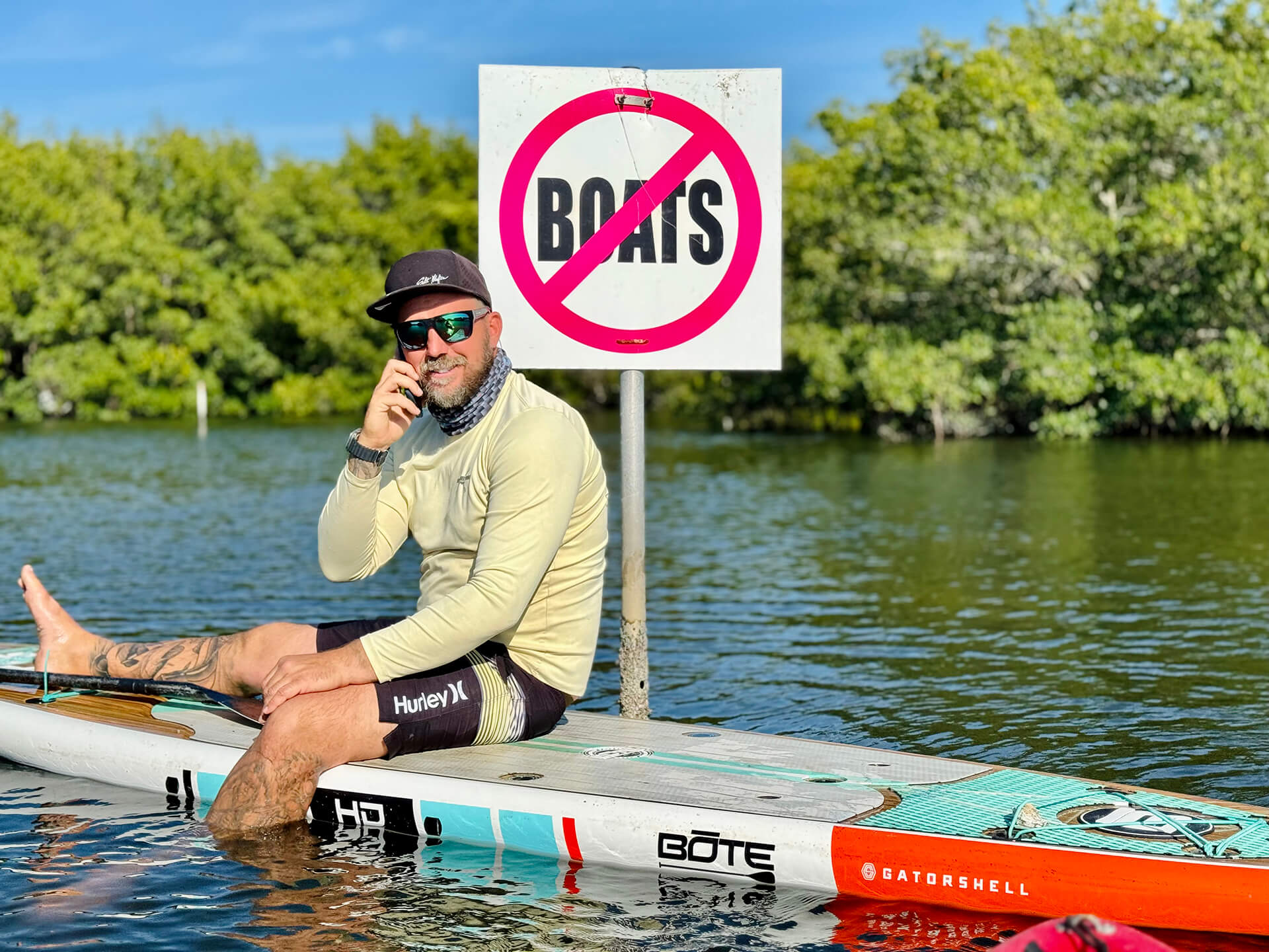 Chad on phone on his paddleboard in front of no boats sign